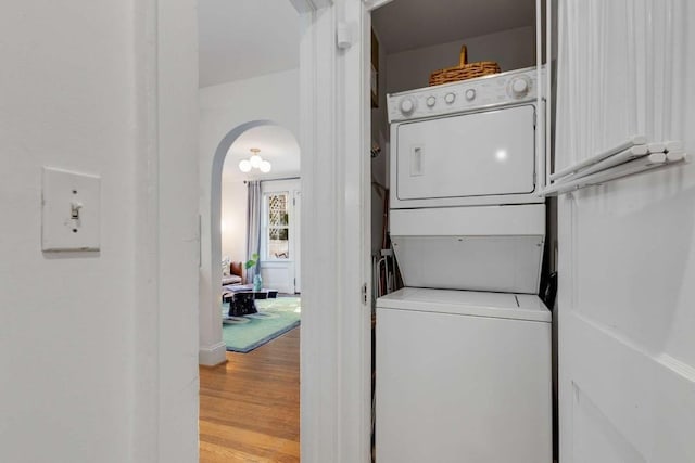 laundry area with stacked washer and clothes dryer and light wood-type flooring