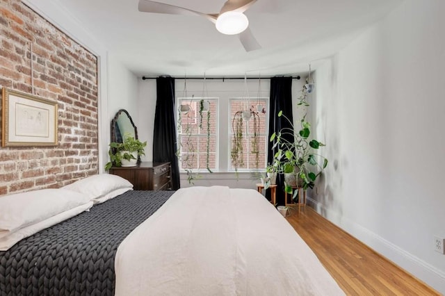 bedroom featuring brick wall, hardwood / wood-style floors, and ceiling fan