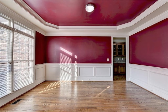 1755 Riverpark Dr, Dacula, GA 30019 - empty room featuring a tray ceiling, ornamental molding, a wainscoted wall, and wood finished floors