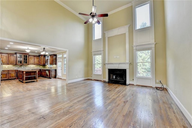 1755 Riverpark Dr, Dacula, GA 30019 - unfurnished living room with a high ceiling, crown molding, ceiling fan, light wood-type flooring, and a fireplace