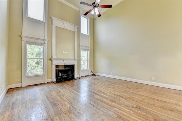 1755 Riverpark Dr, Dacula, GA 30019 - unfurnished living room featuring a premium fireplace, ceiling fan, a high ceiling, crown molding, and wood finished floors