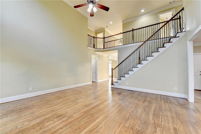 1755 Riverpark Dr, Dacula, GA 30019 - unfurnished living room with crown molding, a ceiling fan, stairway, wood finished floors, and a high ceiling