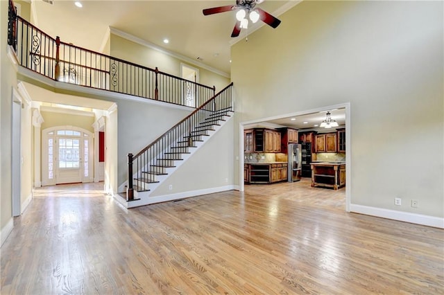 1755 Riverpark Dr, Dacula, GA 30019 - unfurnished living room with a high ceiling, stairway, beverage cooler, ceiling fan, and ornamental molding