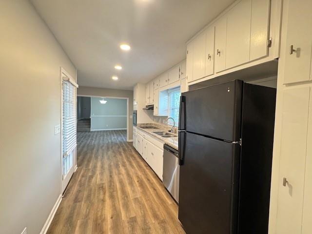 kitchen featuring stainless steel dishwasher, white cabinets, freestanding refrigerator, and a sink