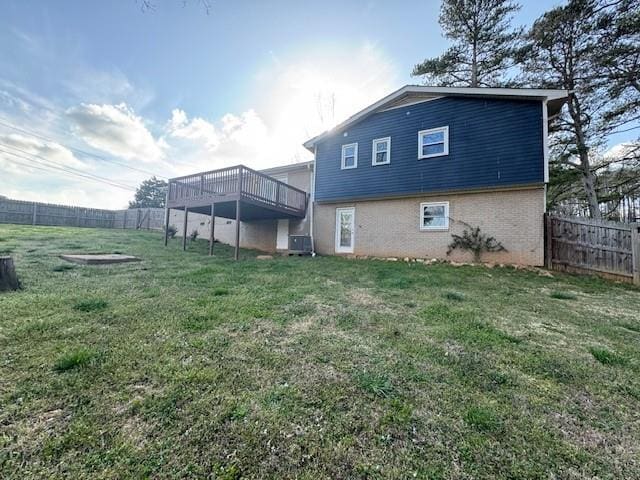 back of property with a fenced backyard, a deck, cooling unit, and a yard