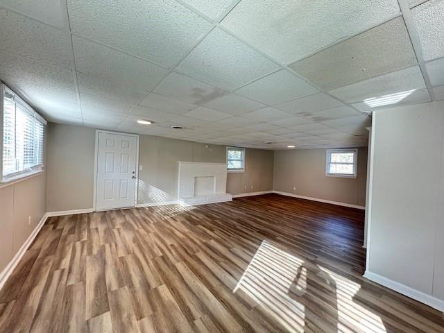 below grade area featuring a drop ceiling, baseboards, and wood finished floors