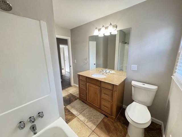 bathroom featuring shower / washtub combination, toilet, vanity, and baseboards