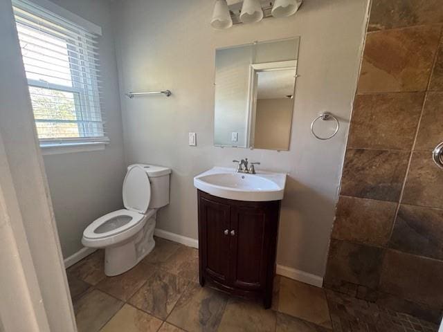 full bath featuring toilet, tiled shower, vanity, and baseboards