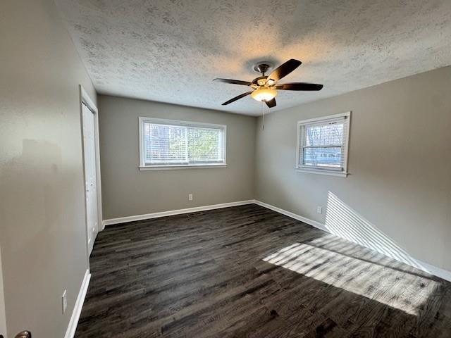unfurnished bedroom with a closet, baseboards, a ceiling fan, a textured ceiling, and dark wood-style floors