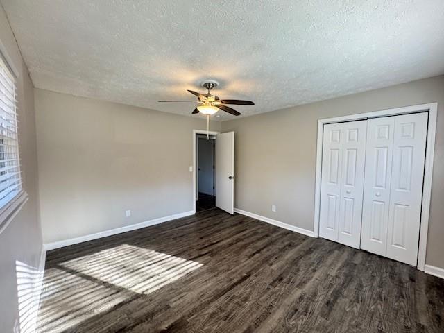 unfurnished bedroom with baseboards, a textured ceiling, ceiling fan, and dark wood-style floors