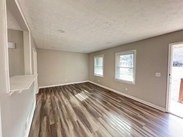 unfurnished living room featuring dark wood-style flooring, baseboards, and a healthy amount of sunlight