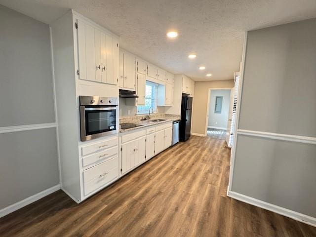 kitchen with baseboards, a sink, dark wood-style flooring, light countertops, and black appliances