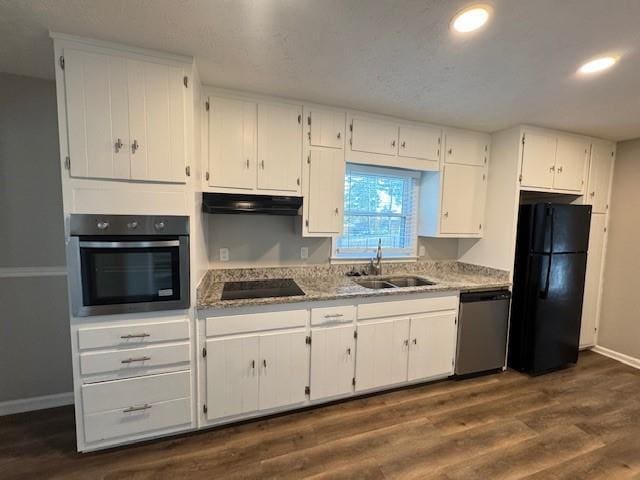 kitchen with dark wood finished floors, white cabinets, black appliances, under cabinet range hood, and a sink