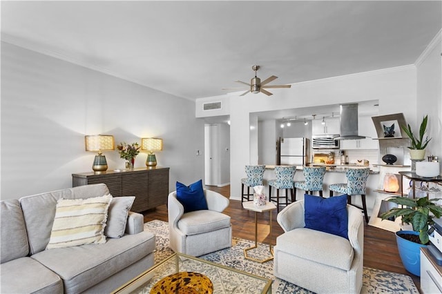 living room featuring wood-type flooring, ornamental molding, and ceiling fan