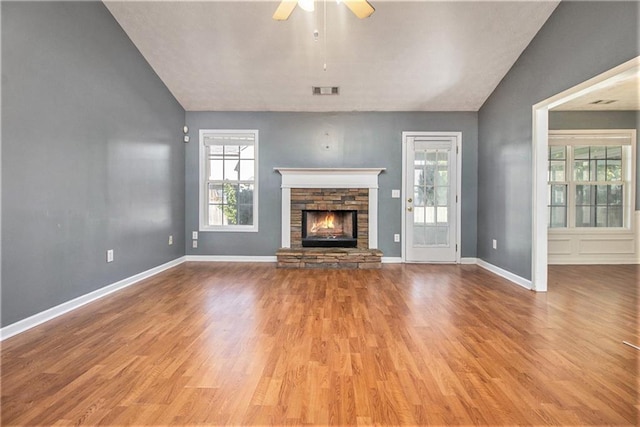 unfurnished living room featuring light wood-type flooring, a fireplace, lofted ceiling, and ceiling fan