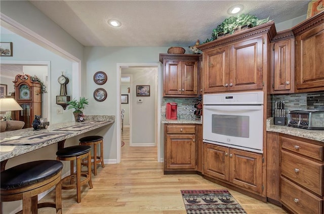 354 Starcross Ln, Jasper, GA 30143 - kitchen with light wood finished floors, oven, and backsplash