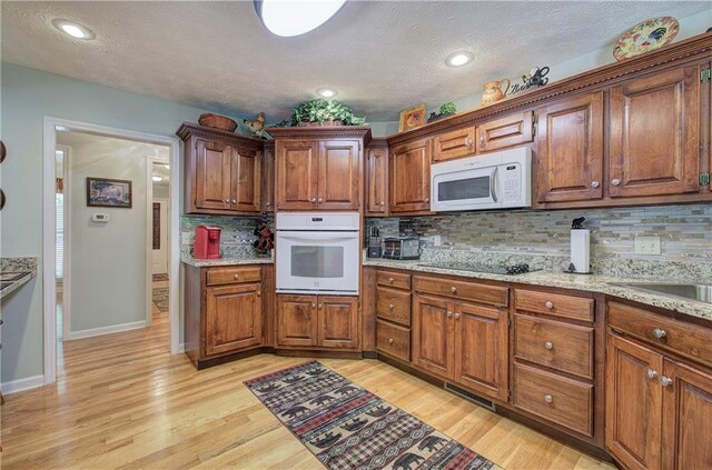 354 Starcross Ln, Jasper, GA 30143 - kitchen featuring light stone countertops, white appliances, backsplash, and light wood-style floors