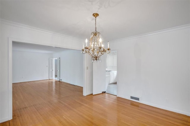 spare room with baseboards, light wood-style flooring, visible vents, and crown molding