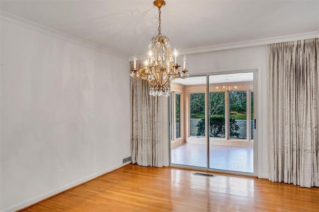 unfurnished room with crown molding, wood finished floors, visible vents, baseboards, and an inviting chandelier