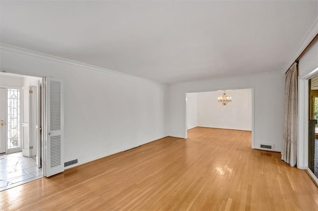 spare room with ornamental molding, light wood finished floors, visible vents, and an inviting chandelier