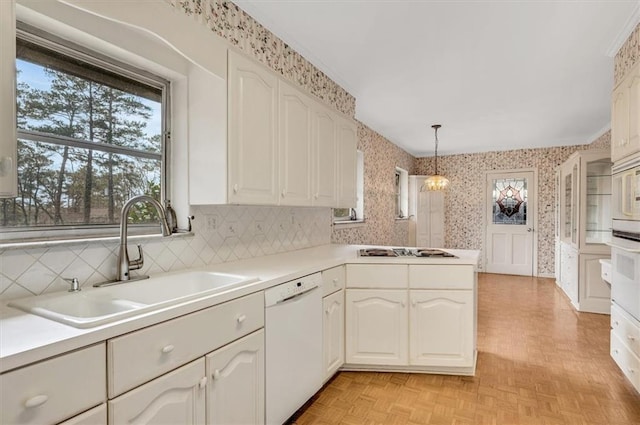 kitchen featuring wallpapered walls, a peninsula, white dishwasher, stovetop, and a sink