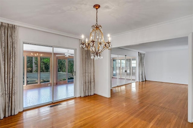 spare room with baseboards, visible vents, ornamental molding, wood finished floors, and ceiling fan with notable chandelier