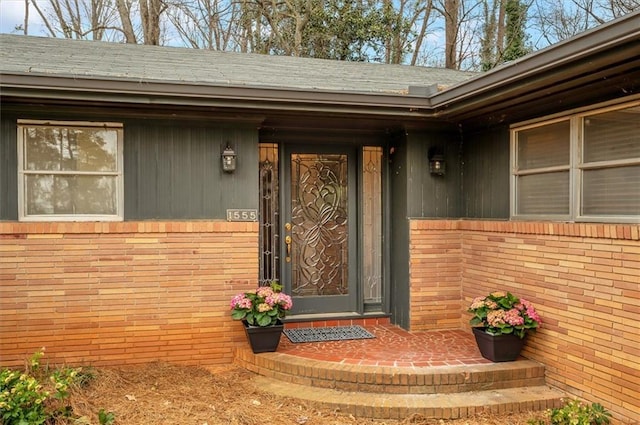 property entrance with brick siding and a shingled roof