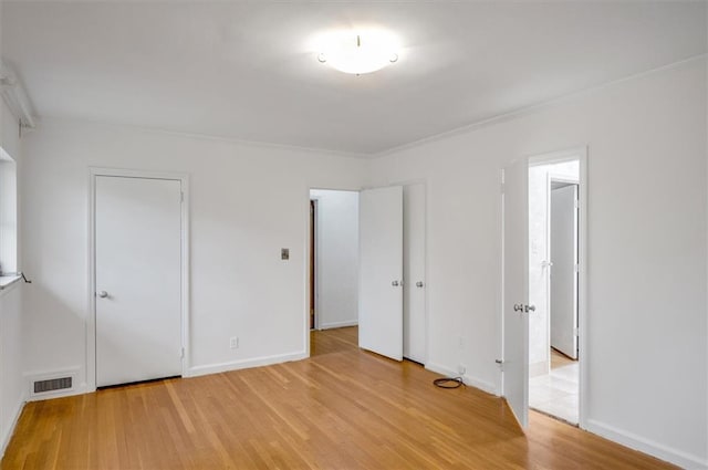 unfurnished bedroom with light wood-type flooring, visible vents, and baseboards