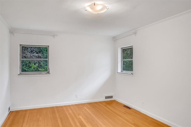 empty room featuring light wood-type flooring, baseboards, and visible vents