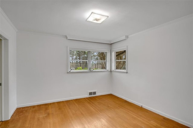 empty room with ornamental molding, visible vents, light wood-style floors, and baseboards