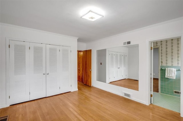 unfurnished bedroom with wood finished floors, visible vents, and crown molding