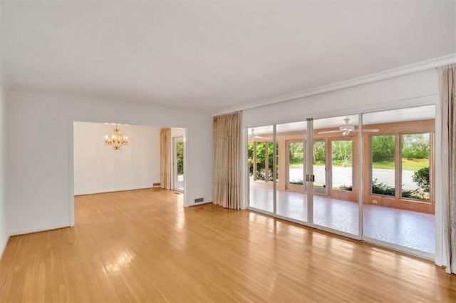 empty room with baseboards, light wood finished floors, ceiling fan with notable chandelier, and crown molding