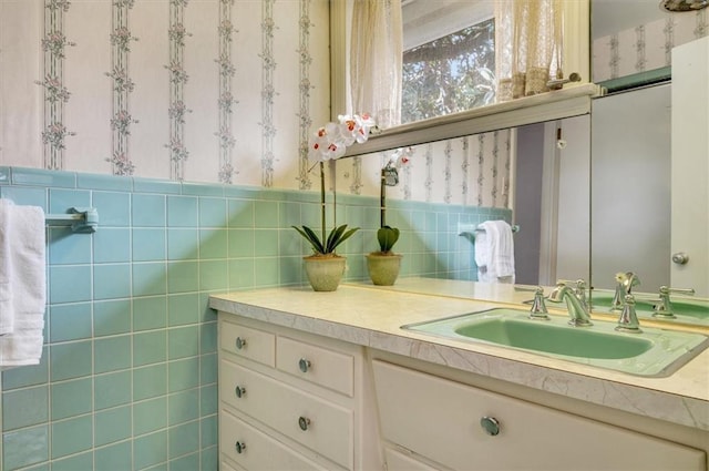 bathroom featuring wallpapered walls, wainscoting, tile walls, and vanity