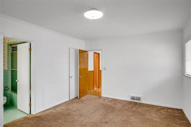 spare room with light carpet, visible vents, and crown molding