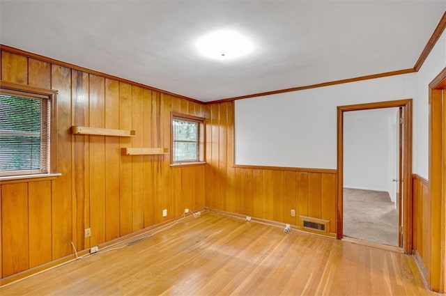 unfurnished room featuring ornamental molding, visible vents, wooden walls, and wood finished floors