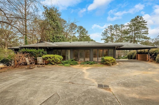 view of front of house featuring a sunroom, an attached carport, and concrete driveway