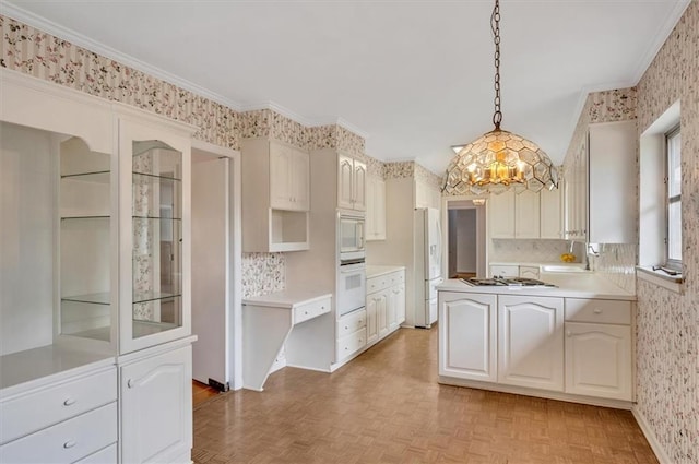 kitchen with a peninsula, white appliances, light countertops, decorative light fixtures, and wallpapered walls