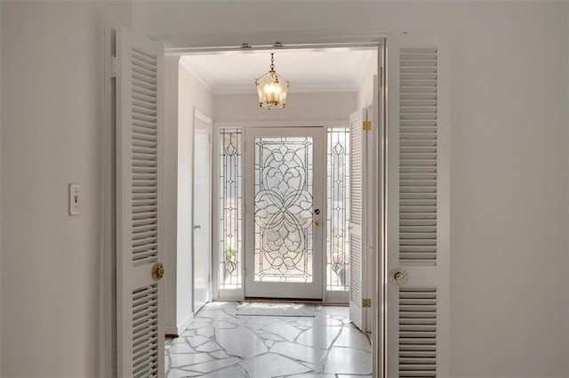 foyer with a notable chandelier, marble finish floor, and crown molding