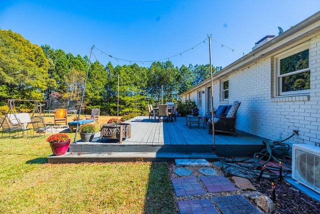 exterior space featuring a trampoline, an outdoor fire pit, a deck, and ac unit