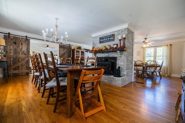 dining area featuring hardwood / wood-style flooring, ornamental molding, a barn door, and ceiling fan