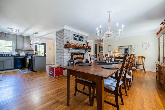 dining space with a brick fireplace, light hardwood / wood-style floors, sink, and a chandelier