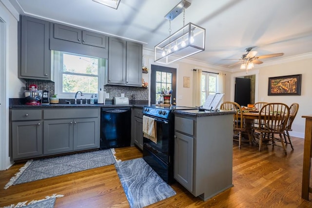 kitchen featuring crown molding, gray cabinetry, hanging light fixtures, black appliances, and kitchen peninsula