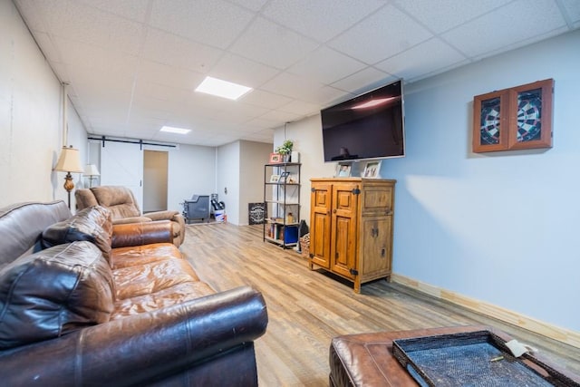 living room featuring a drop ceiling, hardwood / wood-style floors, and a barn door