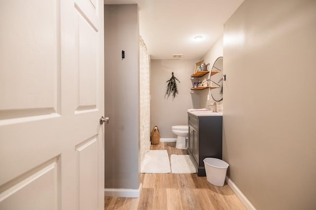 bathroom featuring vanity, wood-type flooring, and toilet