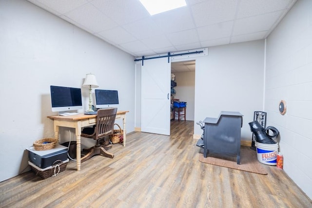 office with hardwood / wood-style flooring, a barn door, and a drop ceiling