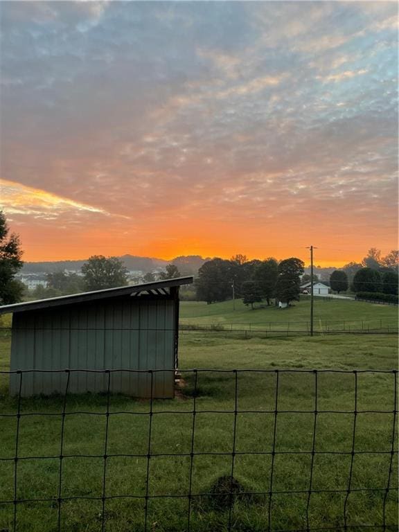 yard at dusk featuring a rural view