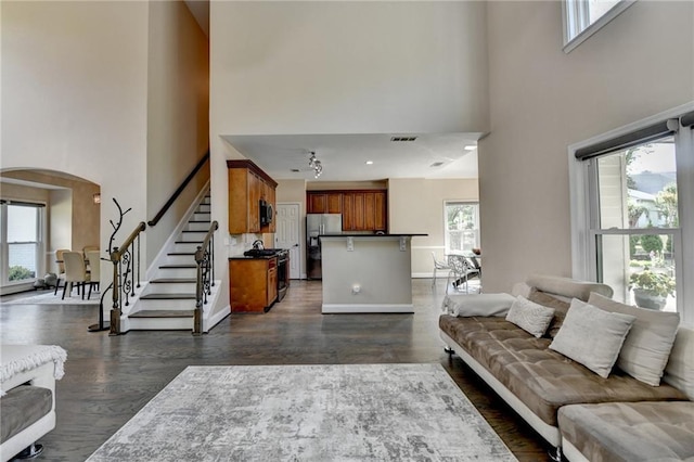 9440 Knollcrest Blvd, Alpharetta, GA 30022 - living room featuring a towering ceiling, arched walkways, dark wood-style floors, stairway, and baseboards