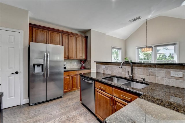 9440 Knollcrest Blvd, Alpharetta, GA 30022 - kitchen with stainless steel appliances, a sink, lofted ceiling, brown cabinetry, and decorative backsplash