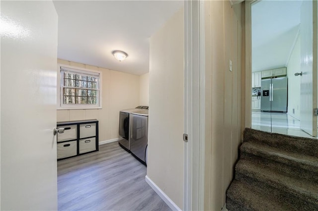 laundry room with washer and clothes dryer and light wood-type flooring