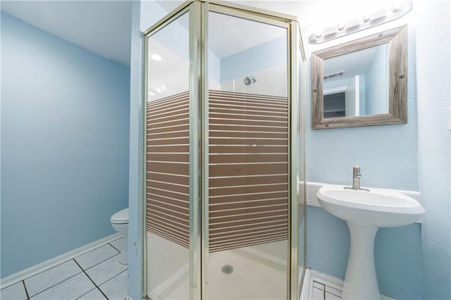 bathroom featuring tile patterned flooring, a shower with door, and toilet